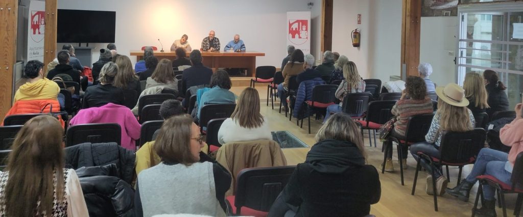 Unas cuarenta personas sentadas escuchan a tres ponentes en una mesa presidencial, durante un encuentro de REASCYL en una sala del Ayuntamiento de Ávila.